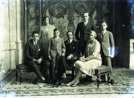Alfonso XIII posando con sus hijos con tapiz como telón de fondo