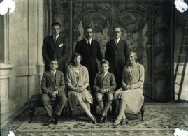 Alfonso XIII posando con sus hijos con tapiz como telón de fondo